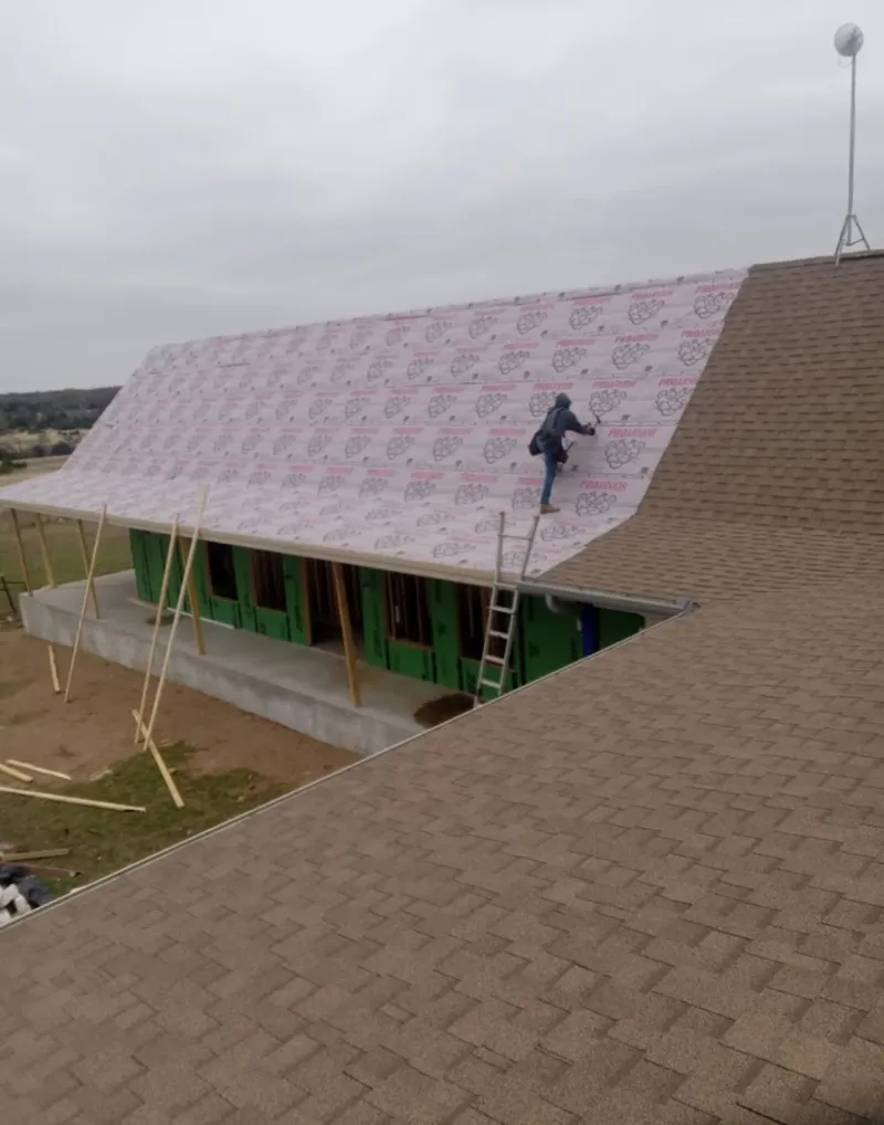 Worker preparing underlayment for a metal roof installation in North Logan